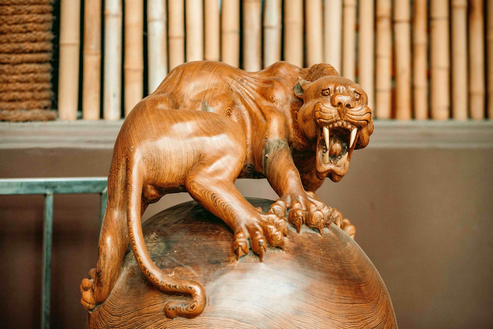 Escultura em madeira de grande felino sobre esfera